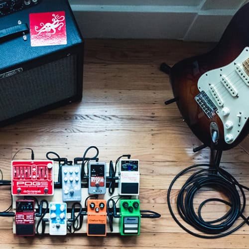 guitar amp and foot pedals on wooden floor